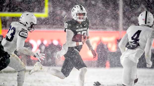 EAST LANSING, MICHIGAN - NOVEMBER 27: Payton Thorne #10 of the Michigan State Spartans runs the ball against Curtis Jacobs #23 and Kalen King #4 of the Penn State Nittany Lions during the fourth quarter at Spartan Stadium on November 27, 2021 in East Lansing, Michigan. (Photo by Nic Antaya/Getty Images)